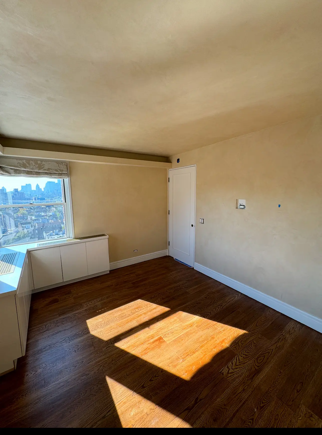 Horatio St. Apartment — primary bedroom with lime-plaster walls and skyline view
